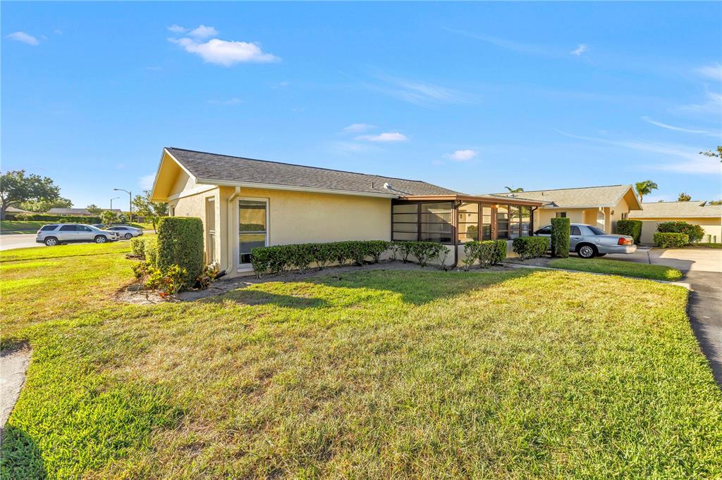 A single-story house with a tan exterior, a screened-in porch, and a grassy front yard — 2740 HIGHLANDS BOULEVARD UNIT B, PALM HARBOR, FL