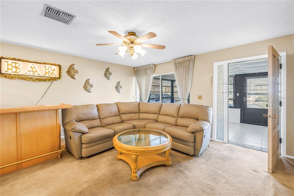 A living room features a beige sectional sofa, a round coffee table, and a home bar — 2740 HIGHLANDS BOULEVARD UNIT B, PALM HARBOR, FL