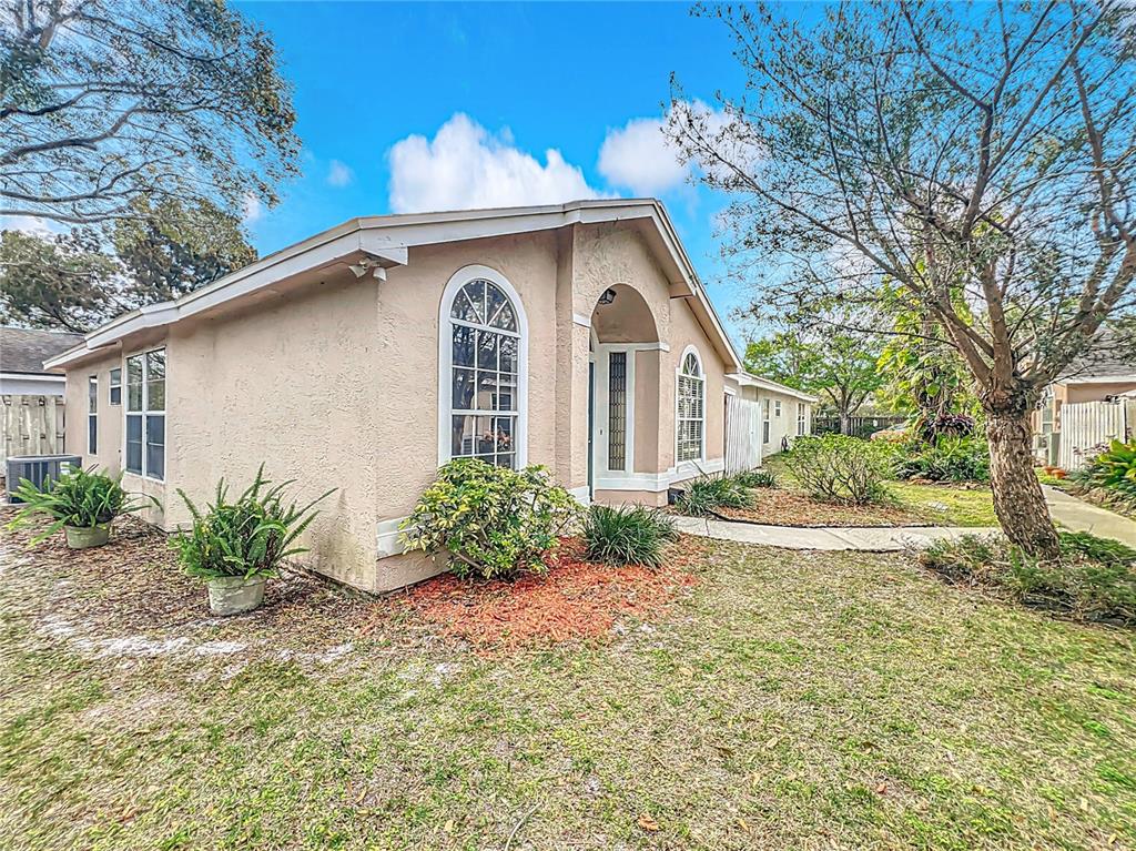 A tan stucco house features an arched window and a covered entryway with landscaping — 310 SUNVISTA COURT, SANFORD, FL