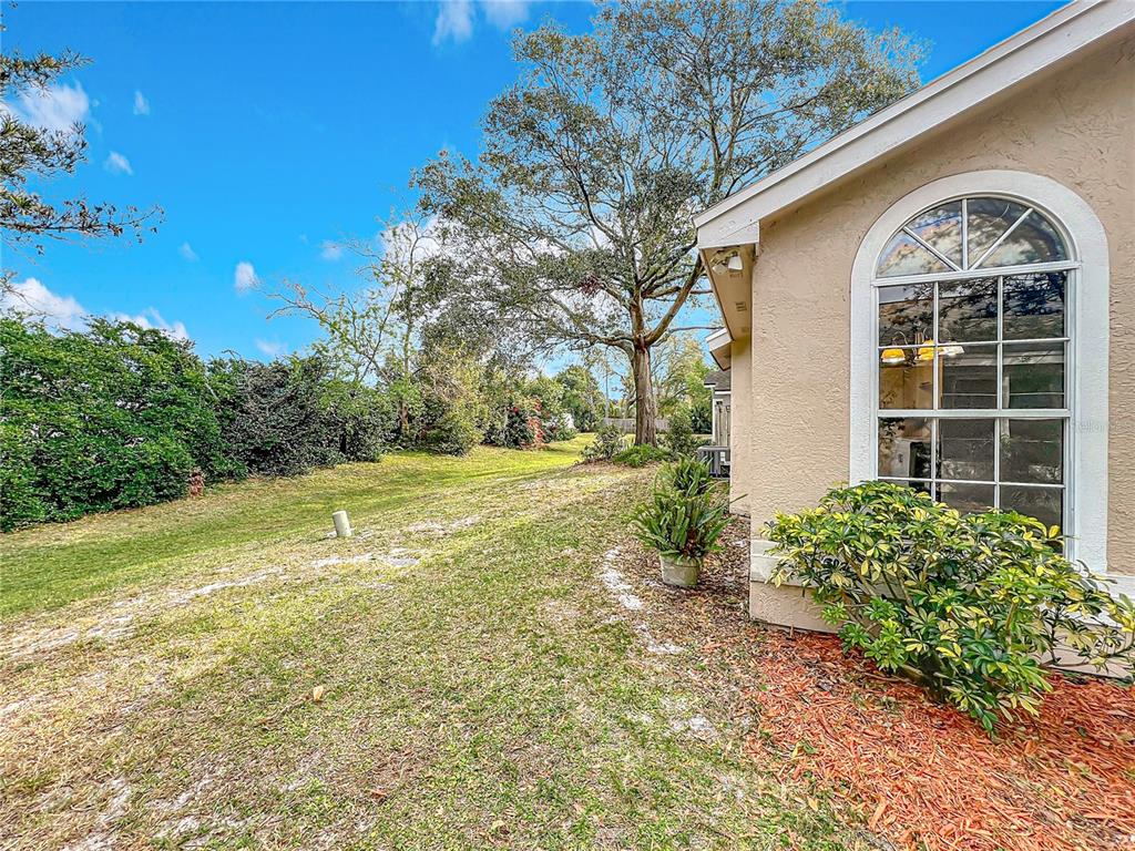 A side view of a house exterior with a large arched window and grassy yard — 310 SUNVISTA COURT, SANFORD, FL