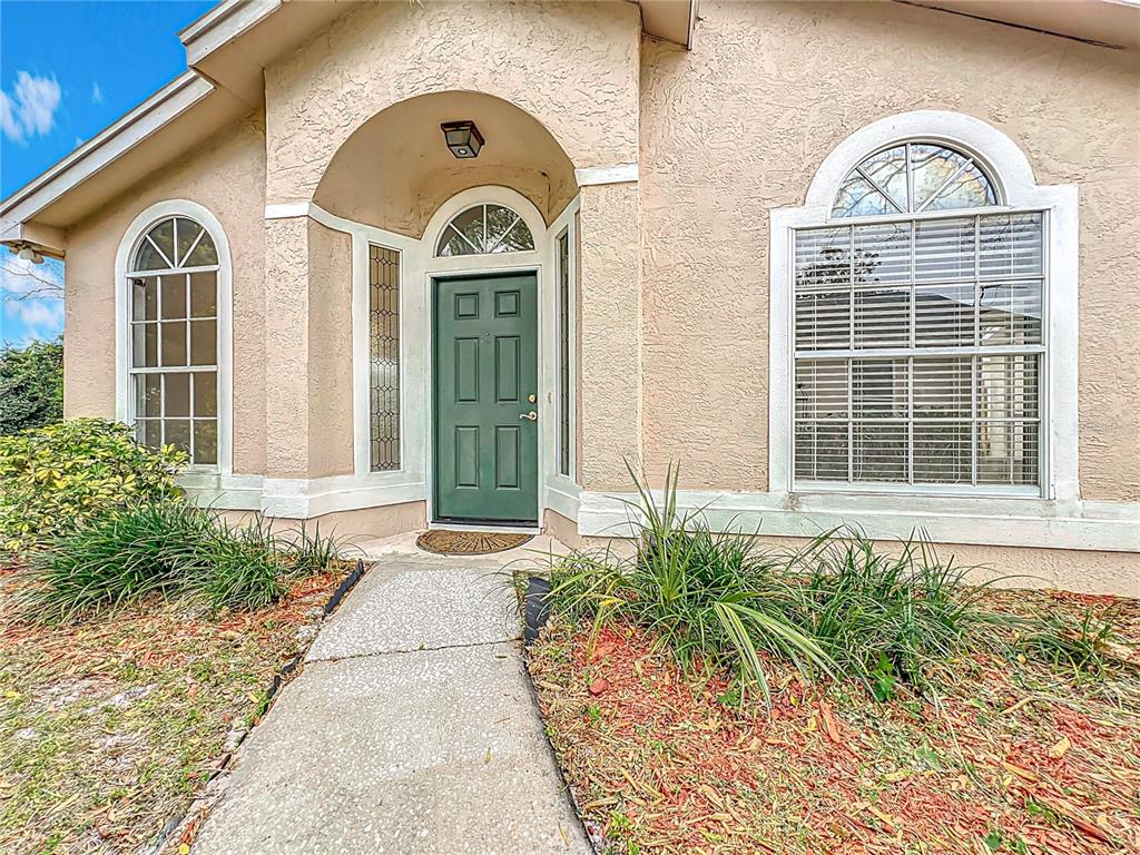 The exterior of a house features a green front door, arched windows, and a walkway — 310 SUNVISTA COURT, SANFORD, FL