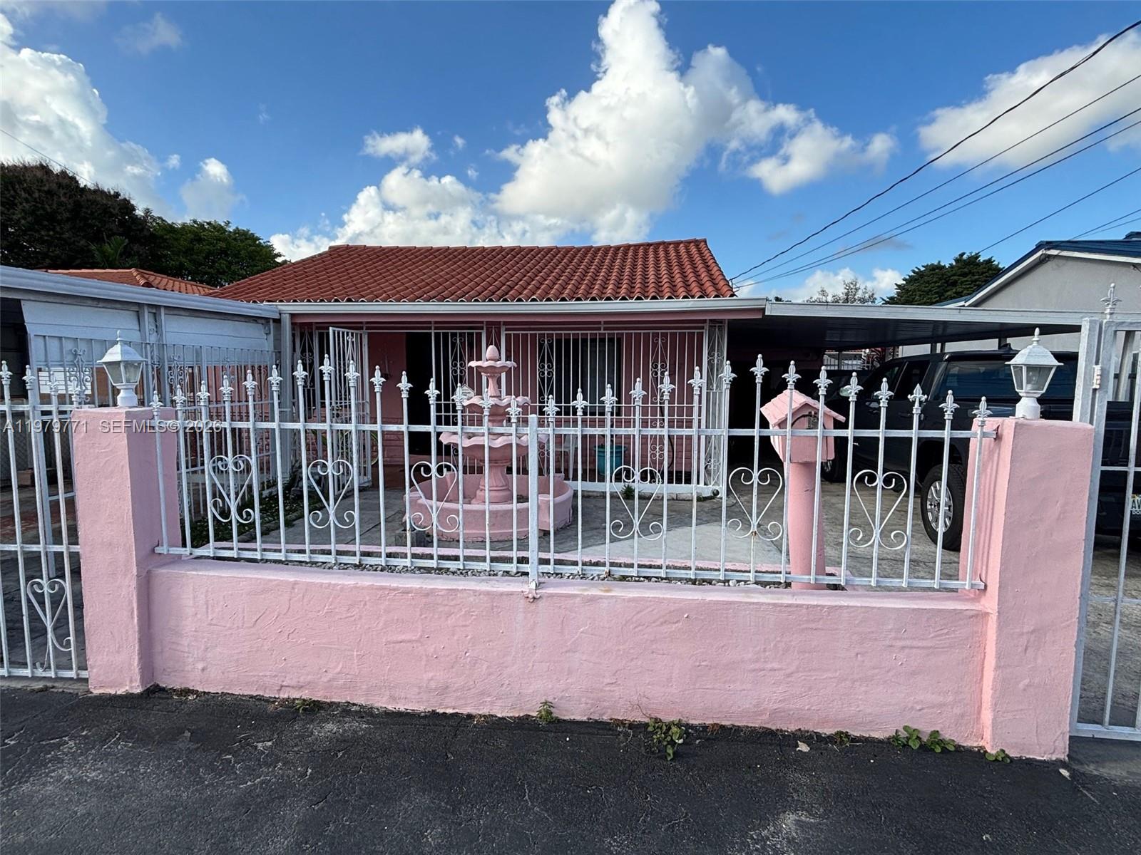 A pink house with a tiled roof, a front fountain, and a decorative metal fence — 3533 NW 2nd Ter, Miami FL 33125, MIAMI, FL