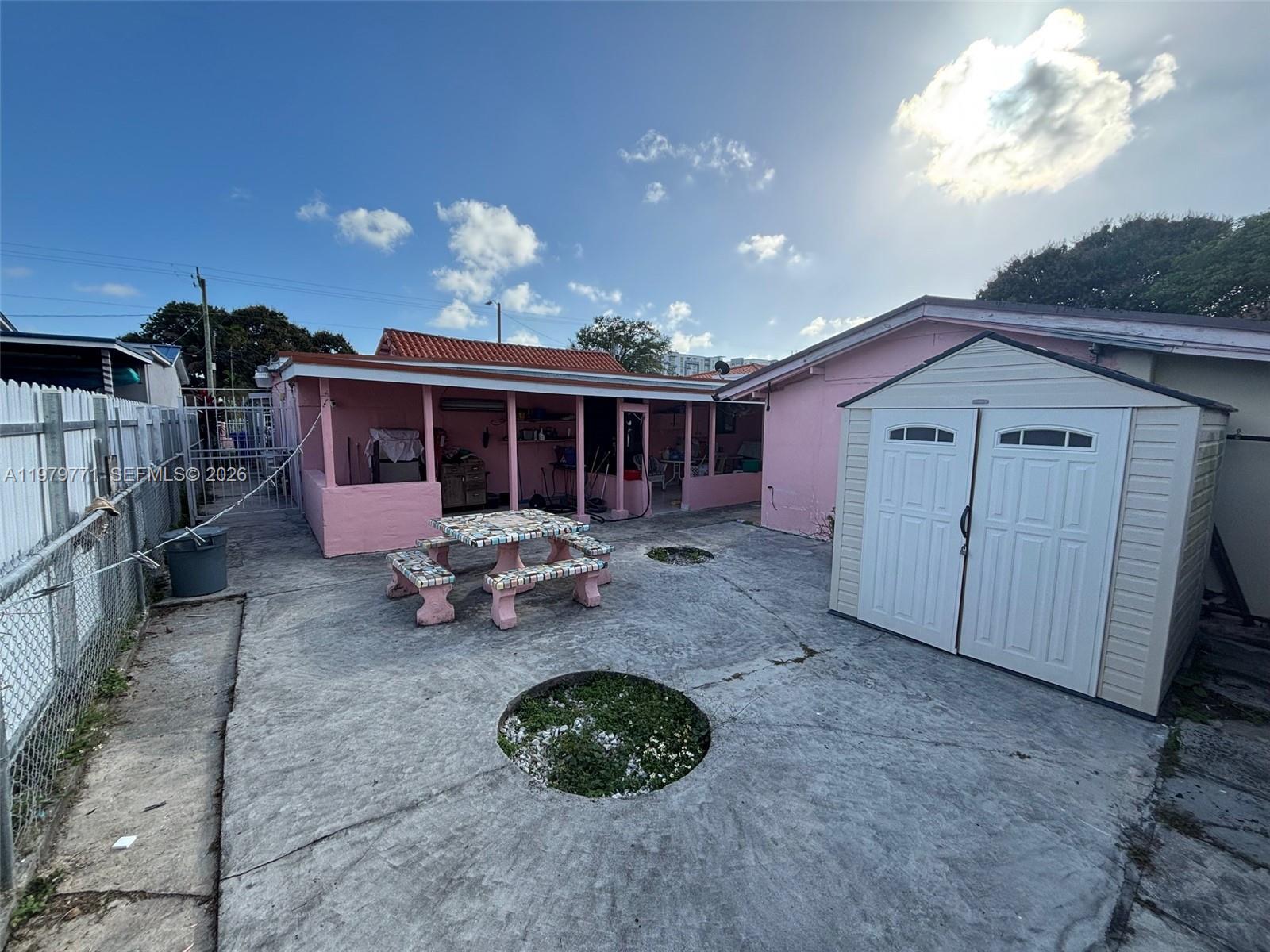 A pink house with a covered patio, a tiled picnic table, and a storage shed — 3533 NW 2nd Ter, Miami FL 33125, MIAMI, FL