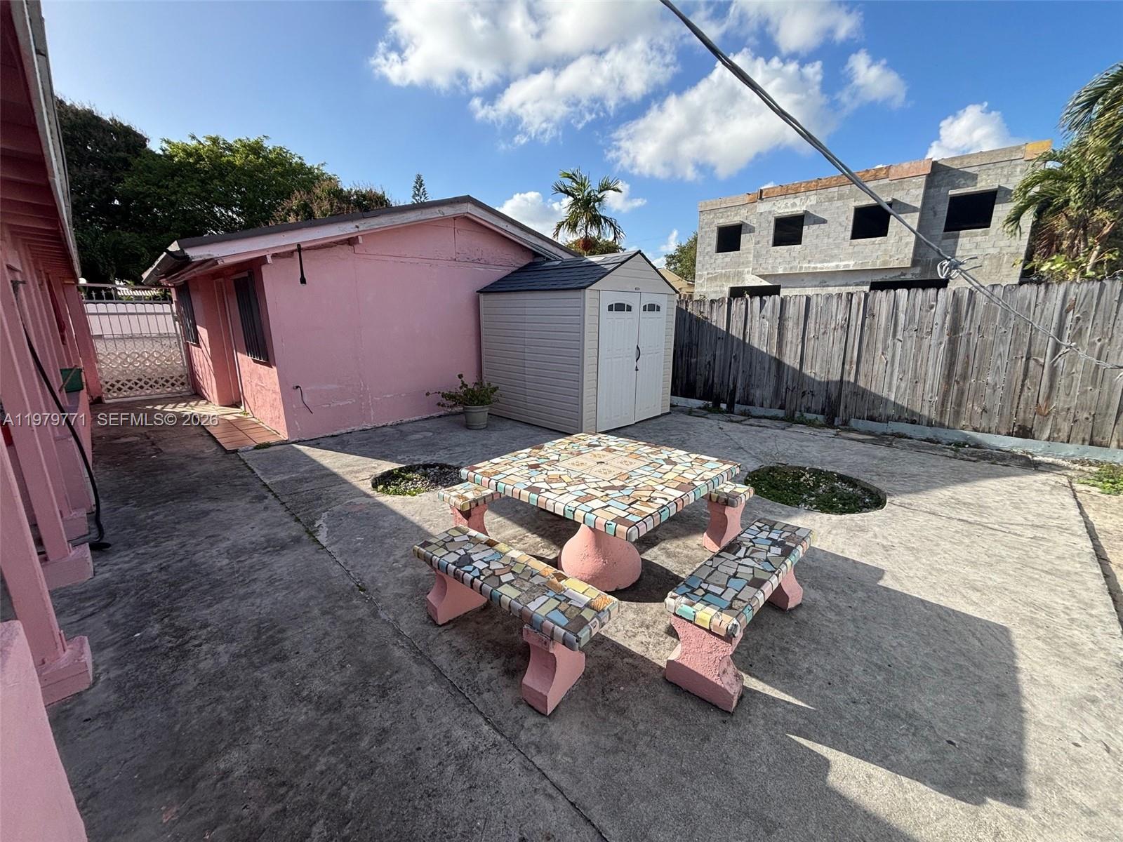 A pink house exterior features a concrete patio with a mosaic table and bench set — 3533 NW 2nd Ter, Miami FL 33125, MIAMI, FL