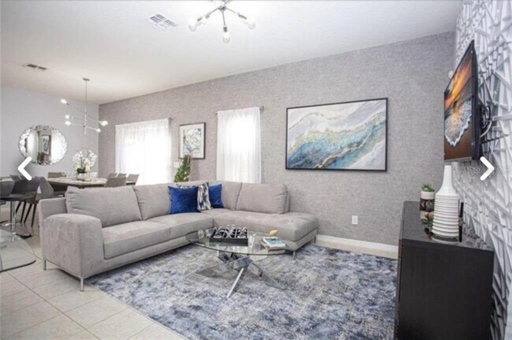 A living room features a gray sectional sofa, a glass coffee table, and textured wallpaper — 1050 LAS FUENTES DRIVE, KISSIMMEE, FL