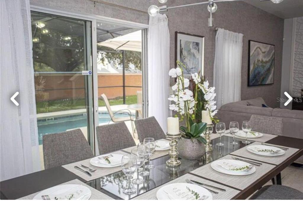 A dining room features a glass-topped table, upholstered chairs, and sliding doors overlooking a pool — 1050 LAS FUENTES DRIVE, KISSIMMEE, FL