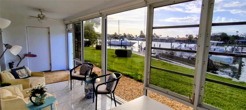 A sunroom with tile floors overlooks a canal with docked boats through large screen windows — 1351 BAYSHORE DRIVE UNIT 108, FORT PIERCE, FL