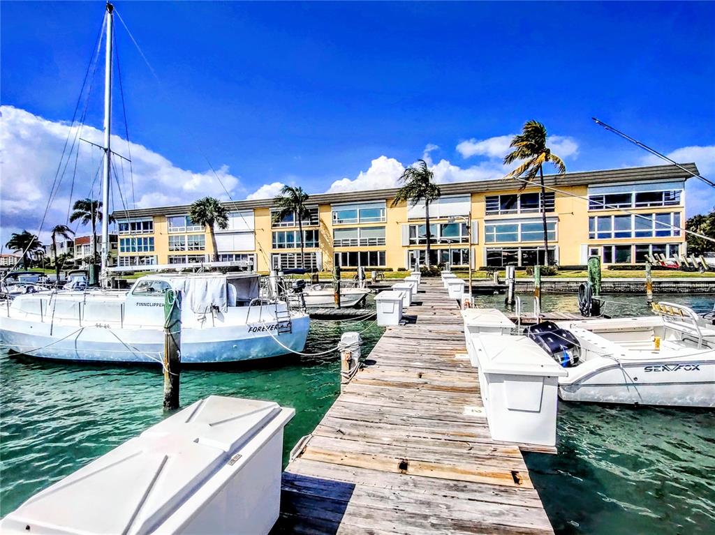 A wooden dock extends toward a multi-story yellow building with boats moored on both sides — 1351 BAYSHORE DRIVE UNIT 108, FORT PIERCE, FL