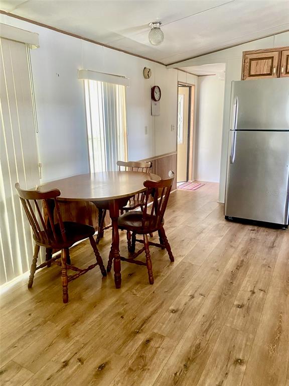 A dining area with a wooden table and chairs sits next to a stainless steel refrigerator — 622 COTTAGE PARK LANE, LEESBURG, FL