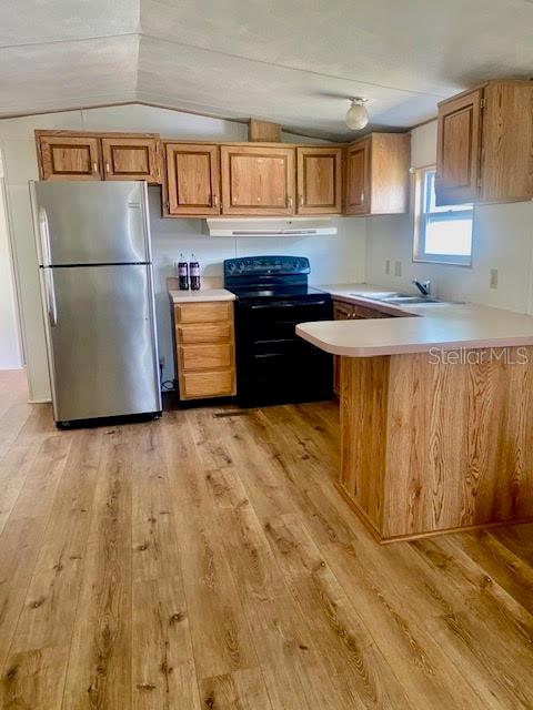 A kitchen features wood cabinets, a stainless steel refrigerator, a black stove, and wood-look flooring — 622 COTTAGE PARK LANE, LEESBURG, FL