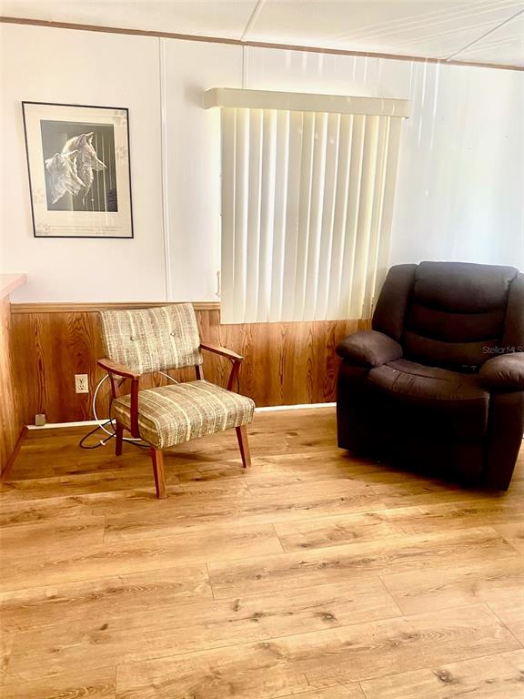 A room features wood-look flooring, wood paneling, a patterned armchair, and a brown recliner — 622 COTTAGE PARK LANE, LEESBURG, FL