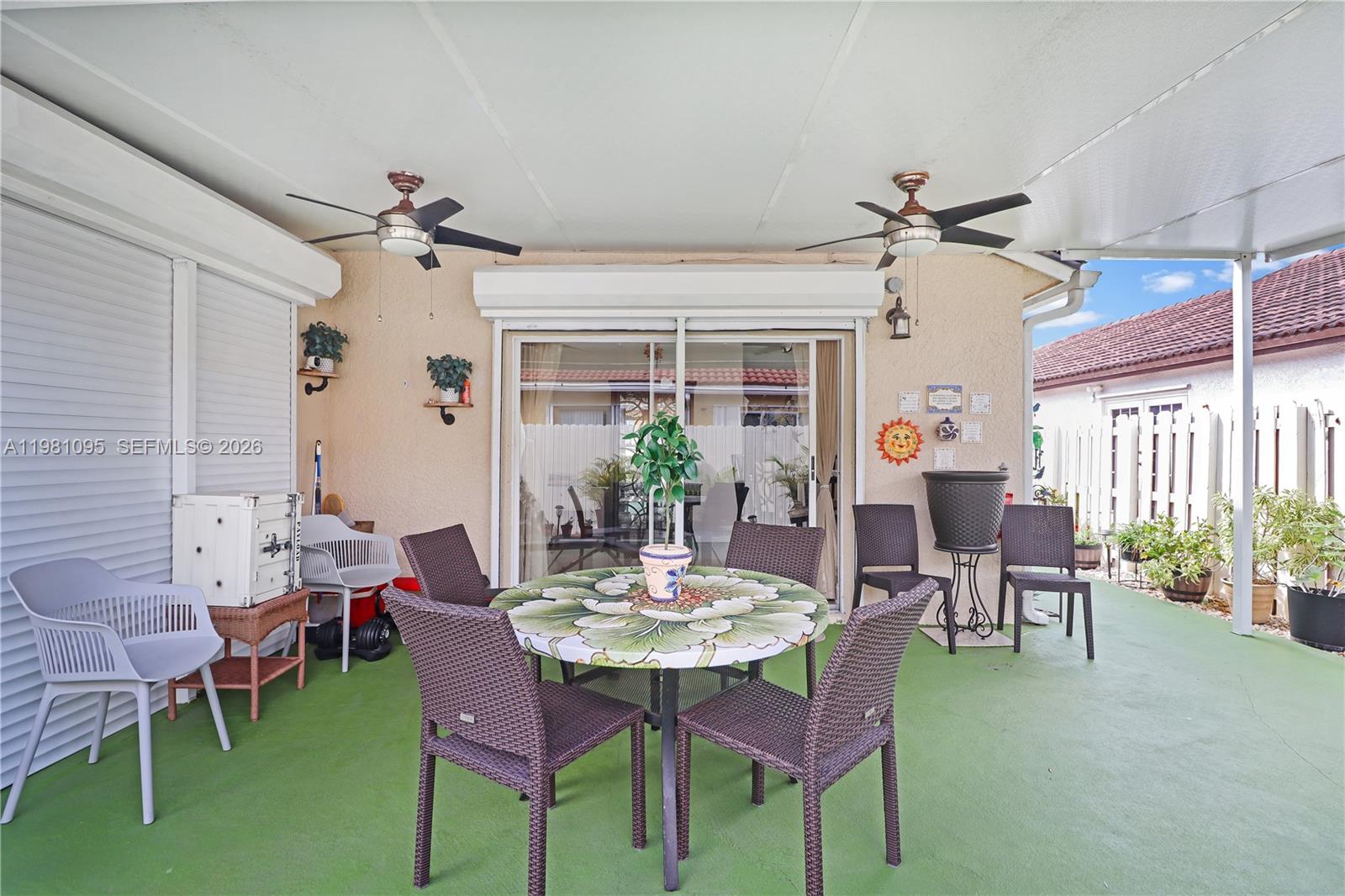 A covered patio features a dining set, ceiling fans, and a green painted floor — 8070 SW 157th Pl, Miami FL 33193, MIAMI, FL