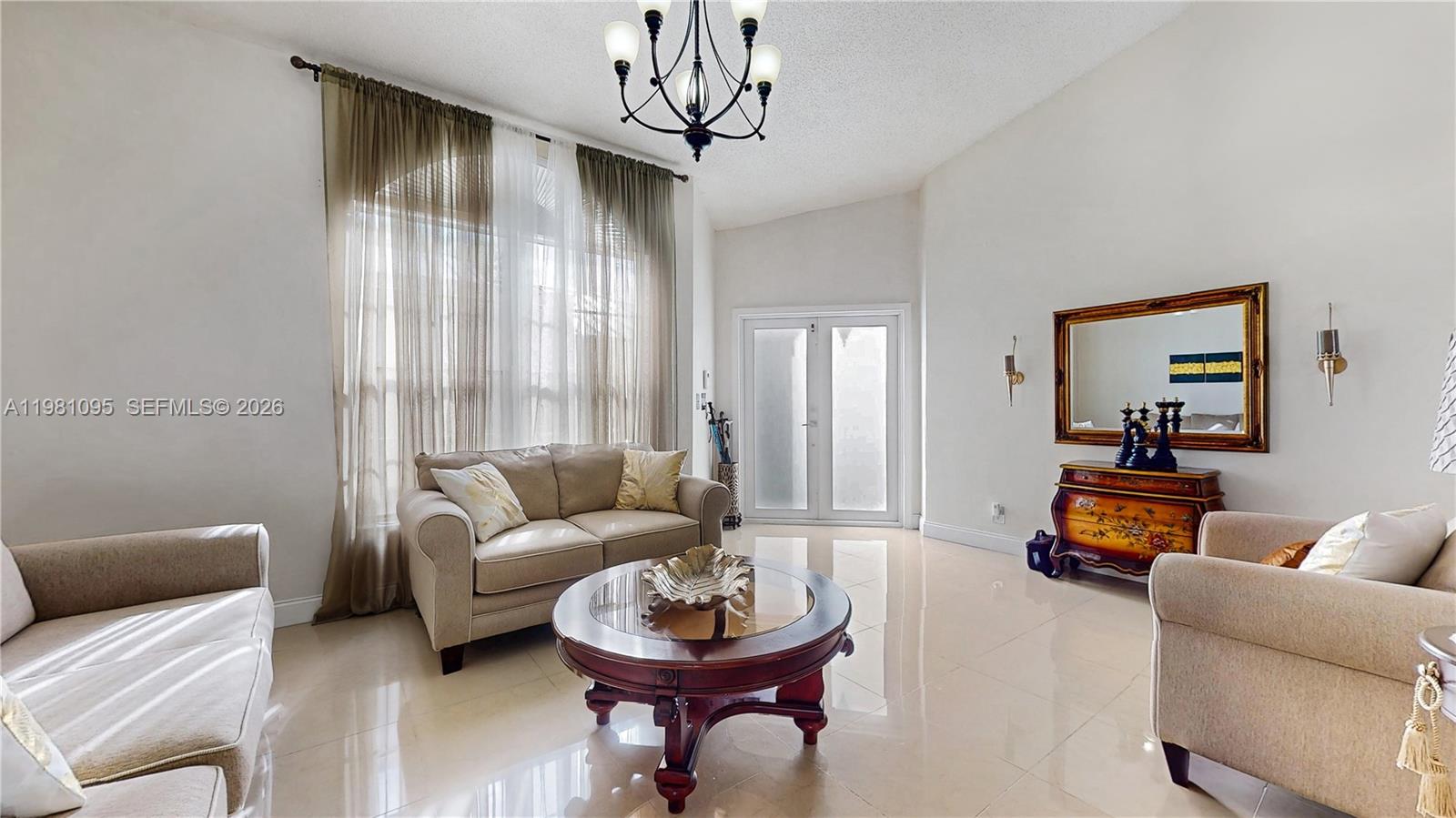 A living room features light-colored tile floors, a chandelier, and a large arched window — 8070 SW 157th Pl, Miami FL 33193, MIAMI, FL