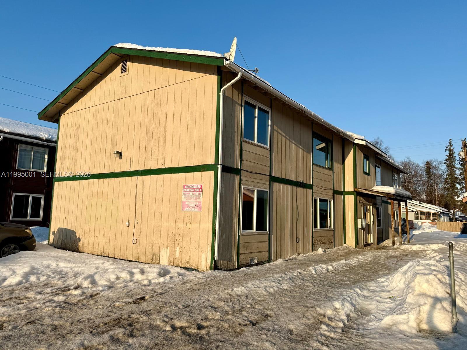 A two-story, tan-sided apartment building with green trim sits on a snow-covered lot — 423 N Lane ST # 4, AK 99508, AK