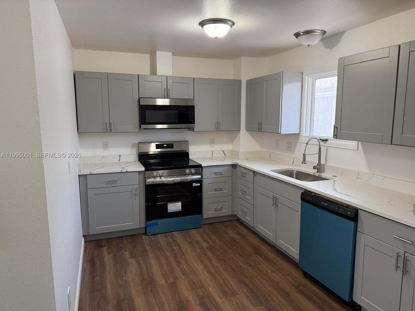 A kitchen features gray shaker cabinets, white marble-look countertops, stainless steel appliances, and wood-look flooring — 423 N Lane ST # 4, AK 99508, AK