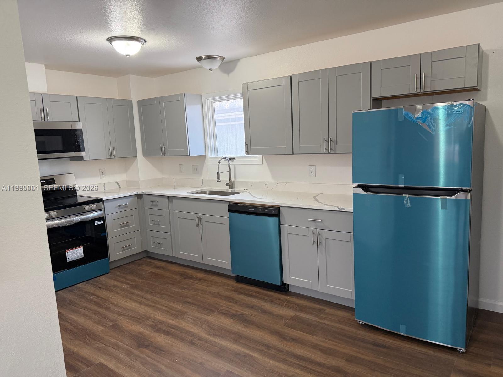 A kitchen features gray cabinets, white marble-patterned countertops, and stainless steel appliances with protective film — 423 N Lane ST # 4, AK 99508, AK