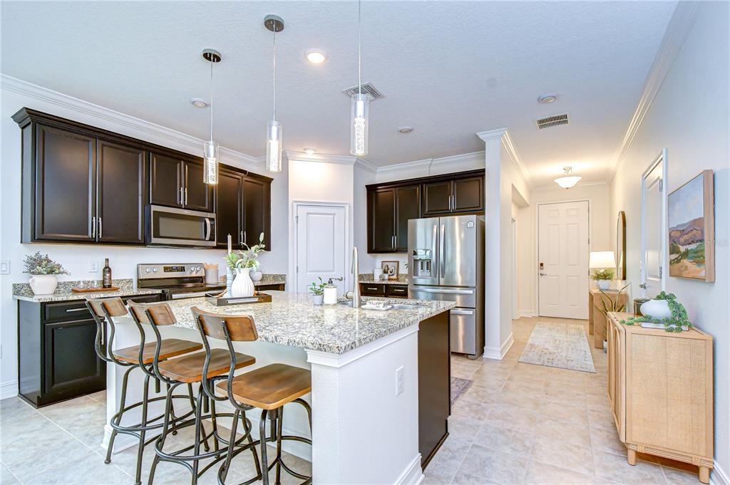A kitchen with dark cabinets, granite countertops, a center island with stools, and stainless appliances — 4749 ROLLING GREEN DRIVE, WESLEY CHAPEL, FL
