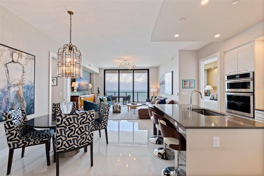A modern open-concept living and dining area features a kitchen island, tile floors, and ocean views — 100 1ST AVENUE N UNIT 2902, ST PETERSBURG, FL