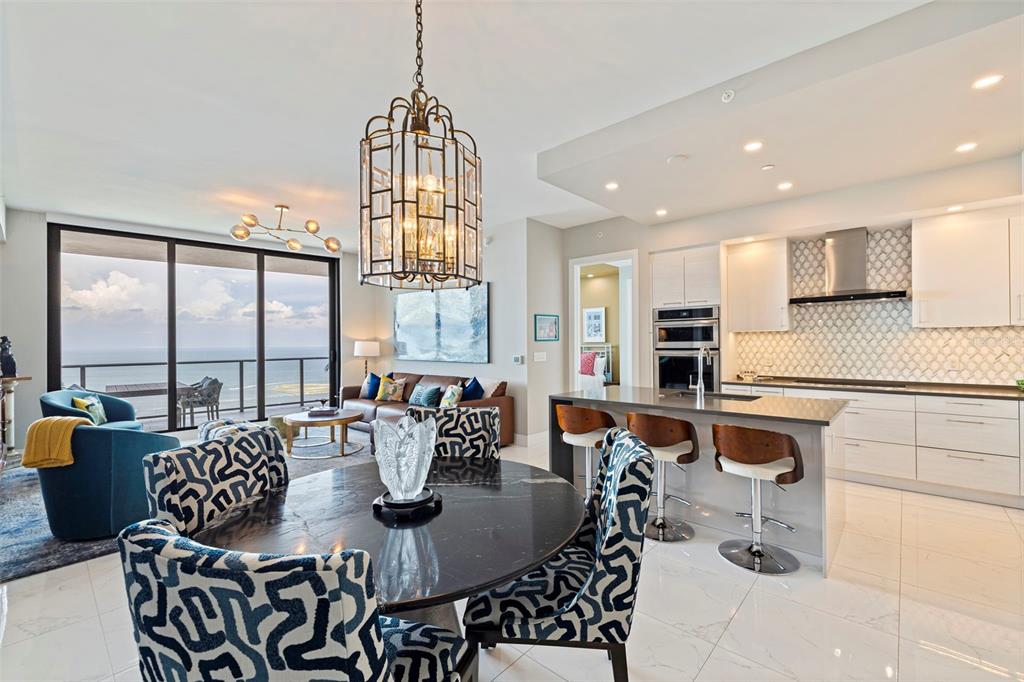 An open-concept living and dining area features a modern kitchen, ocean views, and patterned chairs — 100 1ST AVENUE N UNIT 2902, ST PETERSBURG, FL