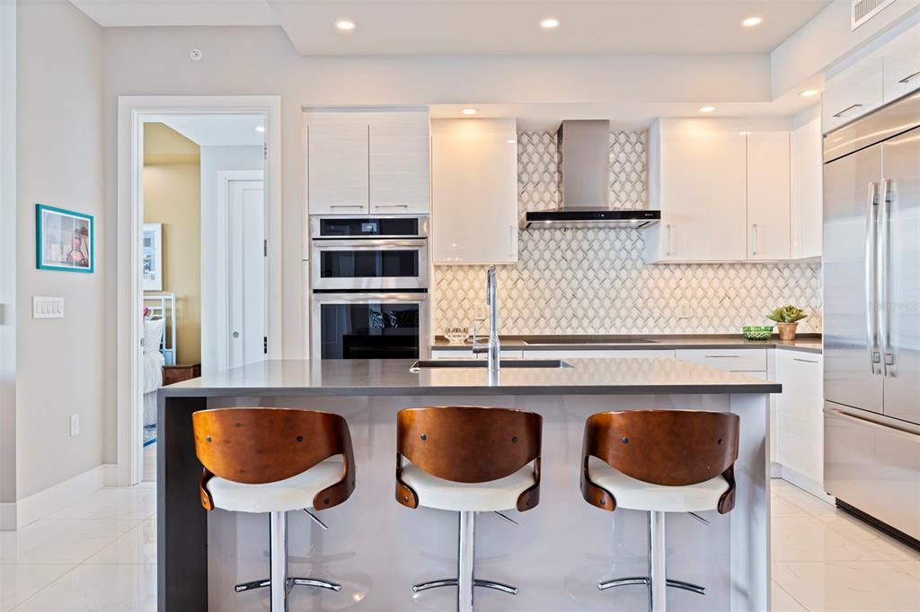A modern kitchen features white cabinetry, stainless steel appliances, a gray island, and three bar stools — 100 1ST AVENUE N UNIT 2902, ST PETERSBURG, FL