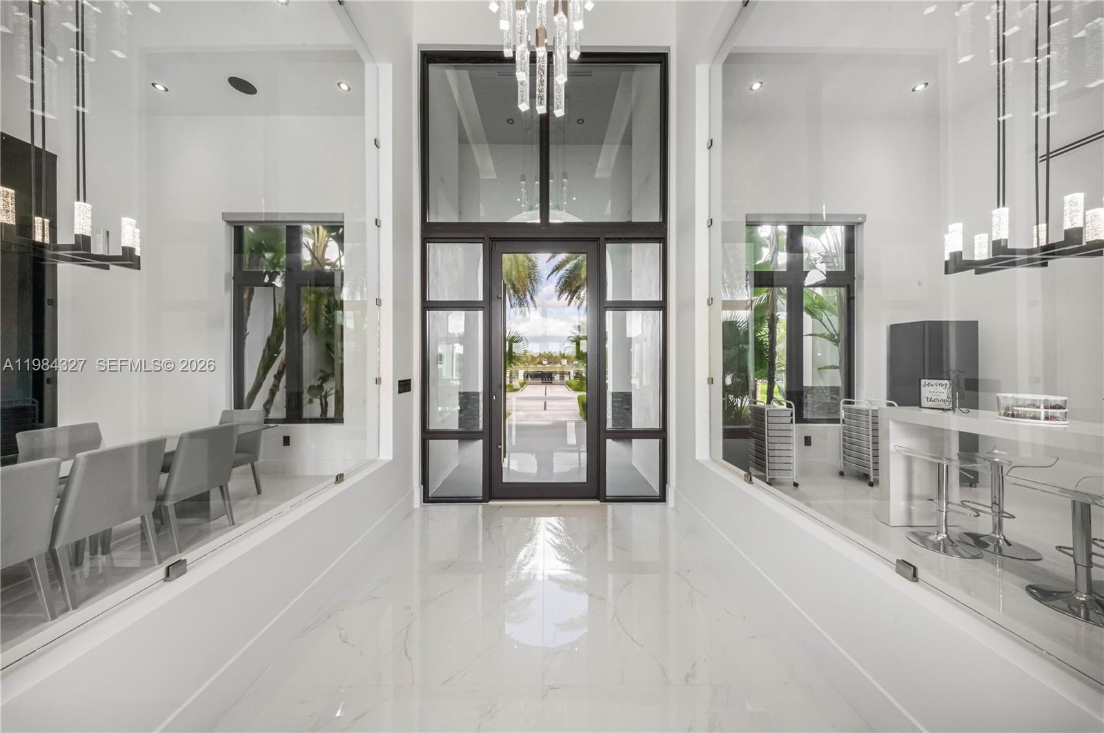 A bright, modern entryway features white marble floors, glass-walled rooms, and a tall central doorway — 15620 SW 188th Ct, Miami FL 33187, MIAMI, FL
