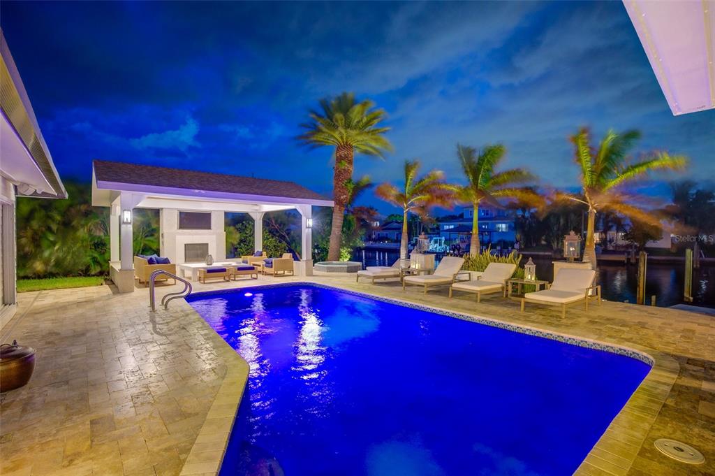 A swimming pool and patio area with a covered lounge space and palm trees — 807 SNUG ISLAND, CLEARWATER, FL