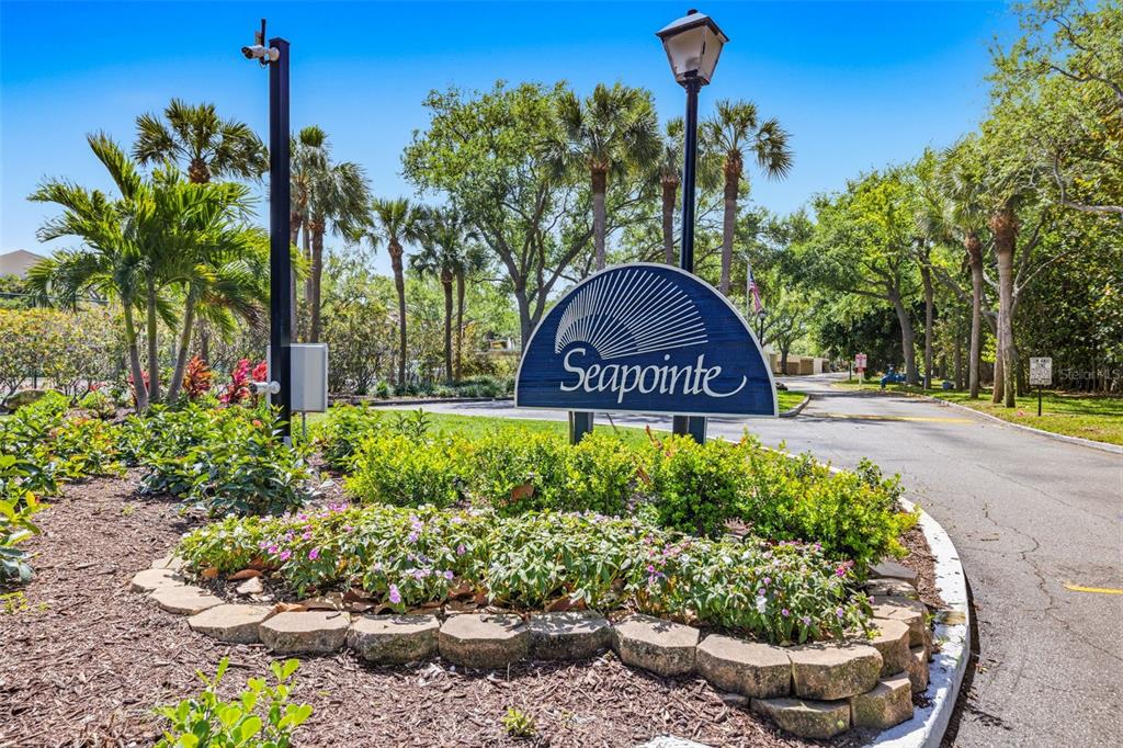 A blue Seapointe community sign stands in a landscaped garden bed beside a paved road — 7520 SUNSHINE SKYWAY LANE S UNIT T22, ST PETERSBURG, FL