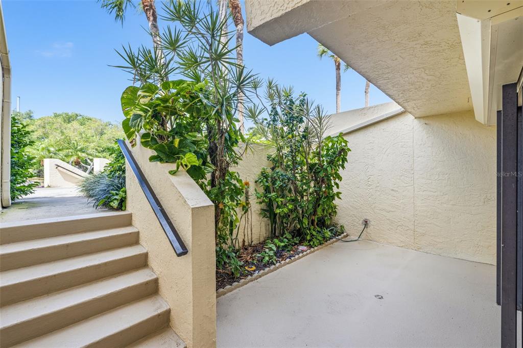 An outdoor concrete staircase leads up to a patio area with lush green plants — 7520 SUNSHINE SKYWAY LANE S UNIT T22, ST PETERSBURG, FL