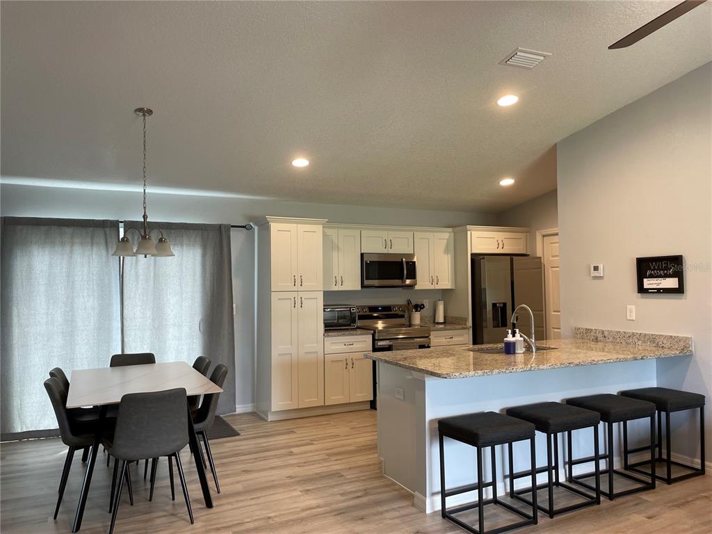 A kitchen with white cabinets, granite countertops, and an island with four bar stools — 16060 SW 23RD COURT ROAD, OCALA, FL