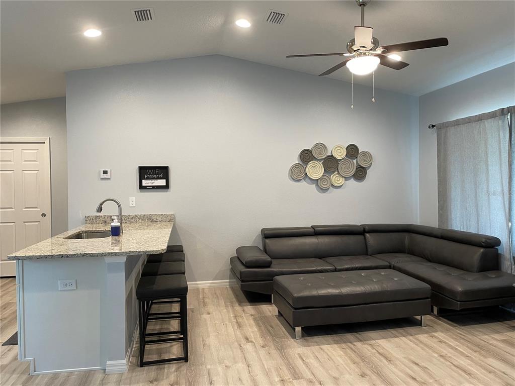 A living room features a grey sectional sofa, a kitchen island with bar stools, and light-colored flooring — 16060 SW 23RD COURT ROAD, OCALA, FL