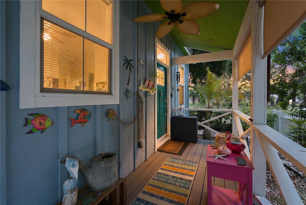 A covered porch with blue siding, a teal door, a ceiling fan, and coastal decor — 559 18TH STREET E, BRADENTON, FL