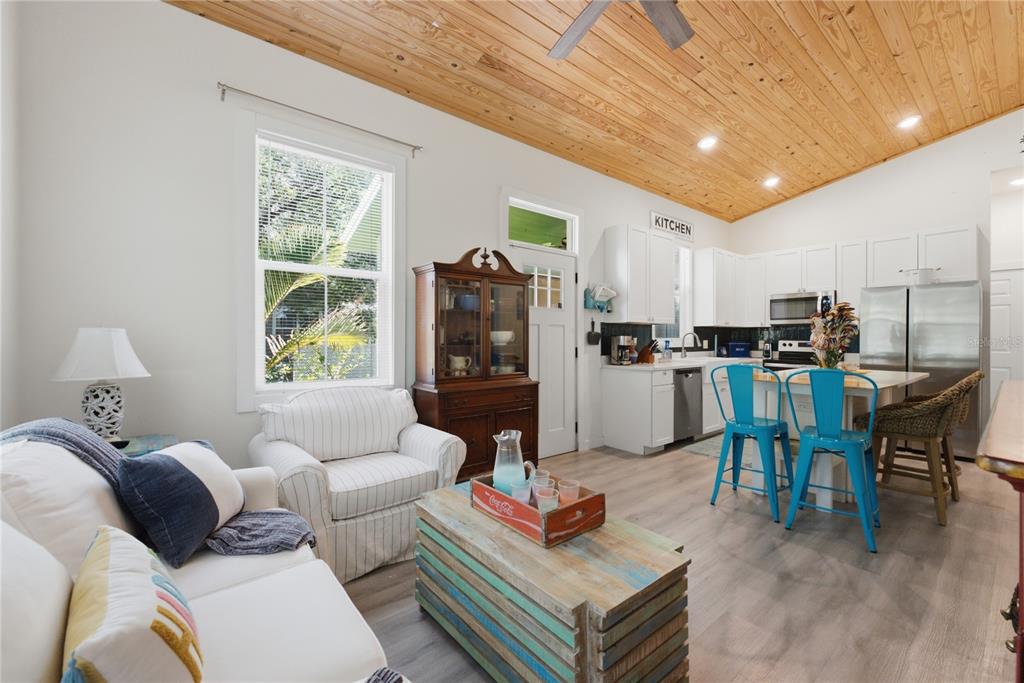 An open-concept living room and kitchen featuring a wood-plank ceiling and light-colored flooring — 559 18TH STREET E, BRADENTON, FL