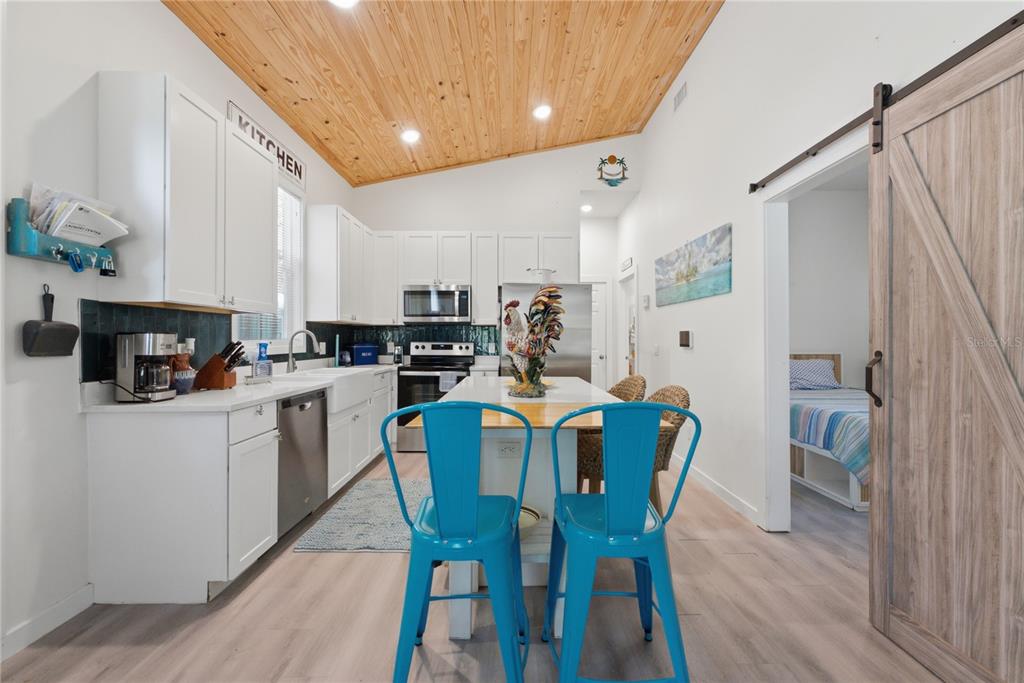 A kitchen with white cabinets, a wood-paneled ceiling, and a central island with blue chairs — 559 18TH STREET E, BRADENTON, FL