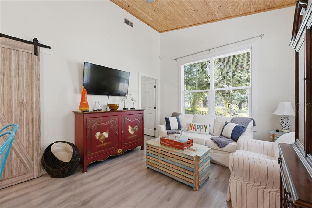 A living room features a red rooster cabinet, a wooden coffee table, and a white sofa — 559 18TH STREET E, BRADENTON, FL
