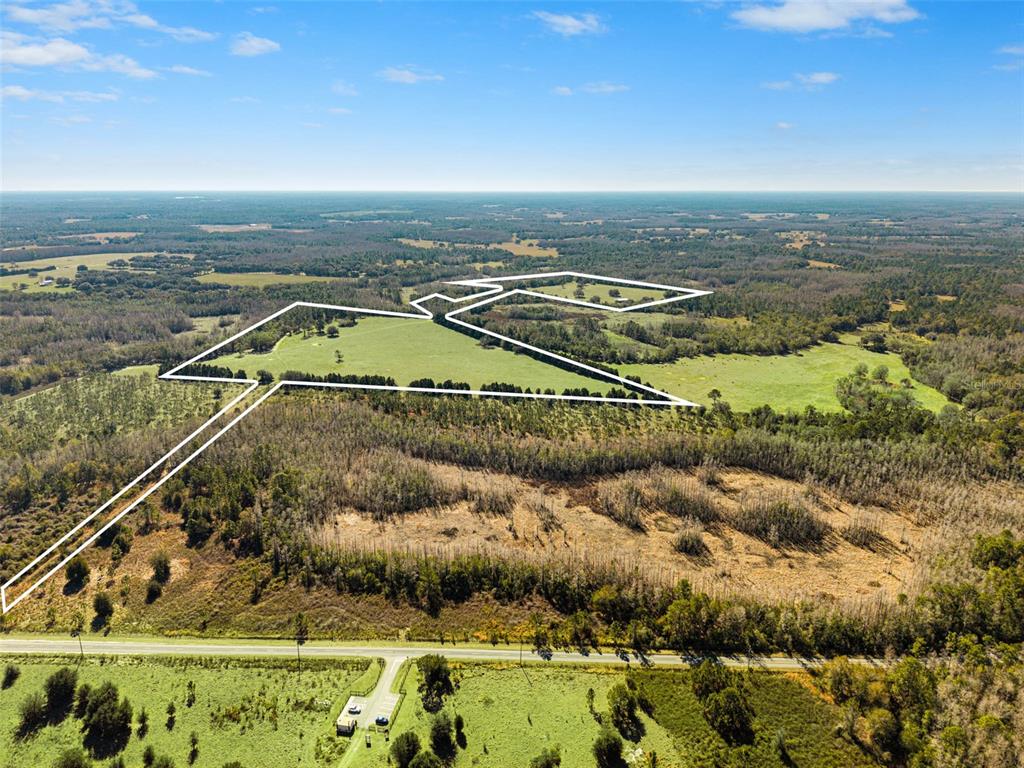 An aerial view shows a large, open grassy field outlined in white against rural land — LAKE ERIE ROAD, GROVELAND, FL