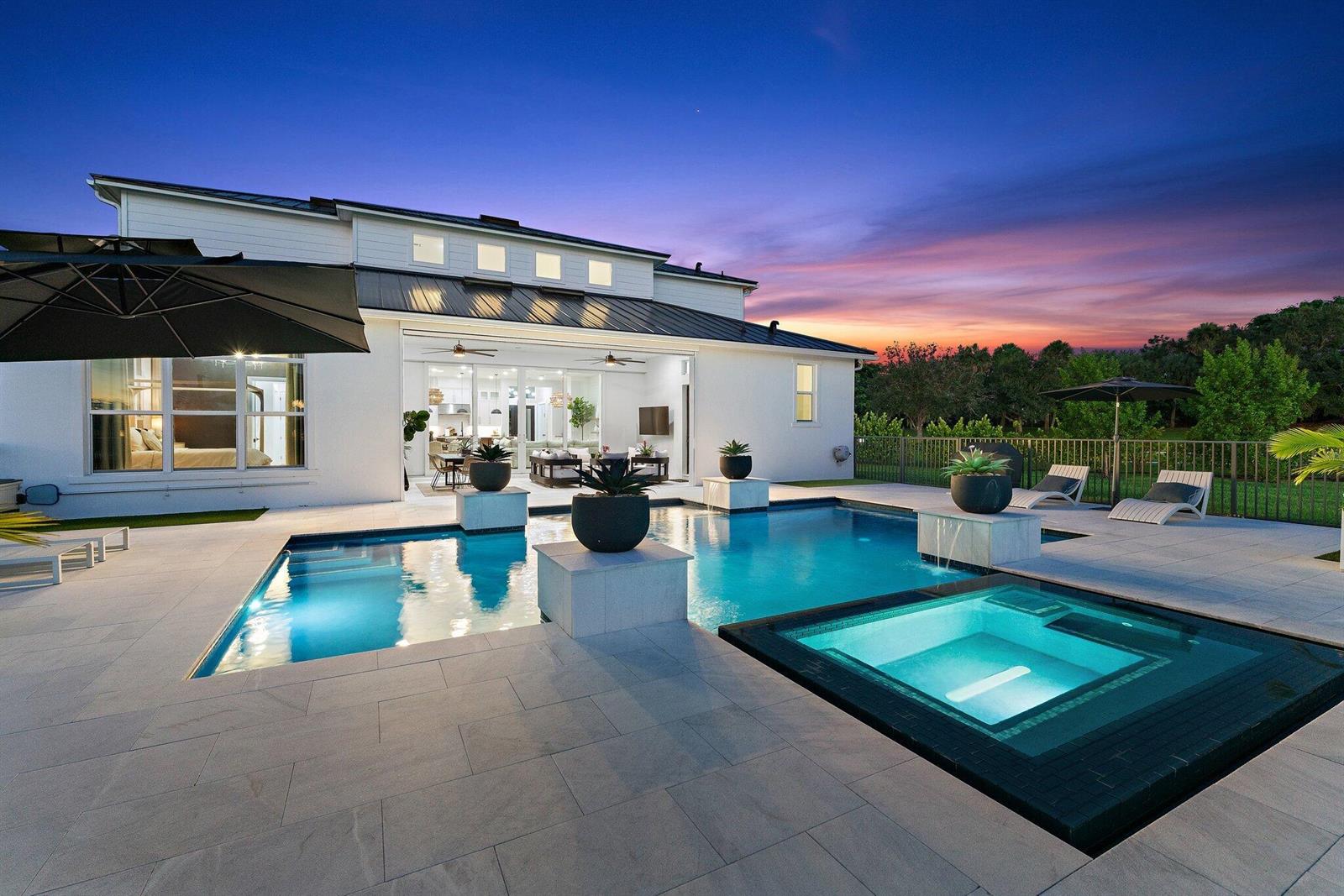 A modern white house features a swimming pool, spa, and patio at sunset — 20124 SE Bridgewater Drive, Jupiter FL 33458, JUPITER, FL