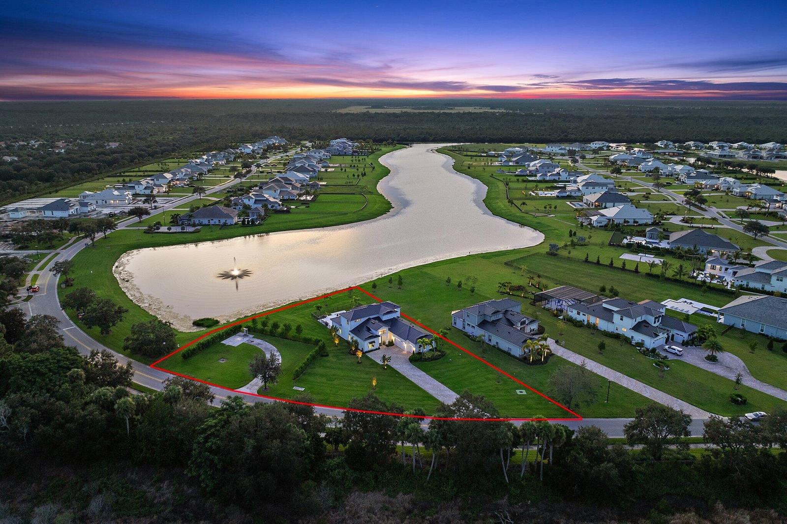 An aerial view shows a modern house on a large corner lot beside a lake — 20124 SE Bridgewater Drive, Jupiter FL 33458, JUPITER, FL