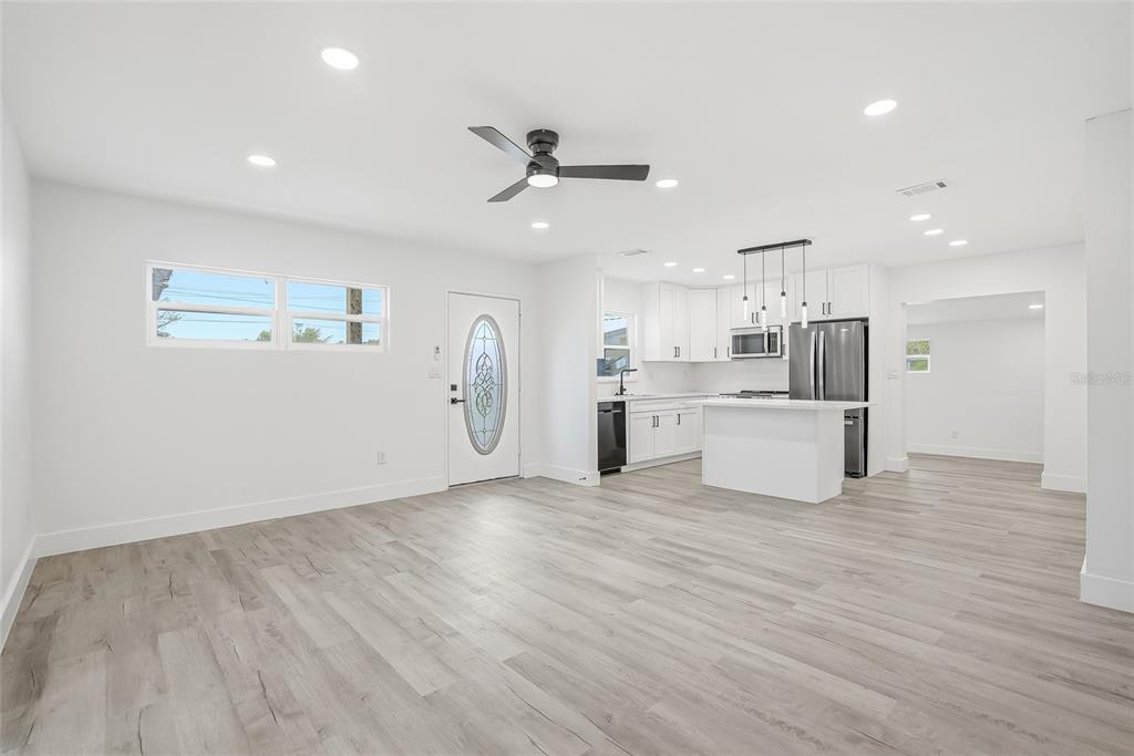 An open-concept living area features white walls, light wood-look flooring, and an adjacent modern kitchen — 529 FIREFLY LANE, APOLLO BEACH, FL
