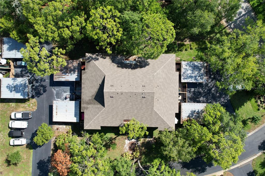 An aerial view shows a multi-unit residential building with a shingled roof and carports — 1006 LENNOX ROAD W UNIT 1006, PALM HARBOR, FL