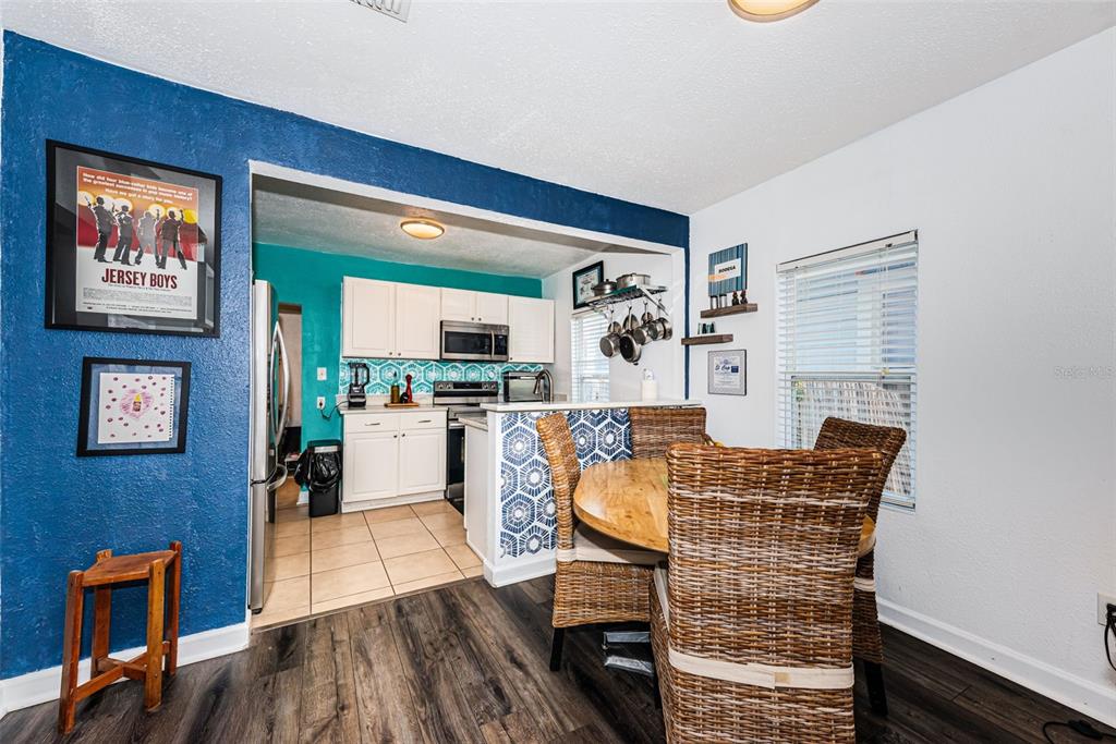 A dining area with a round wooden table and wicker chairs sits beside a kitchen — 547 15TH STREET N, ST PETERSBURG, FL