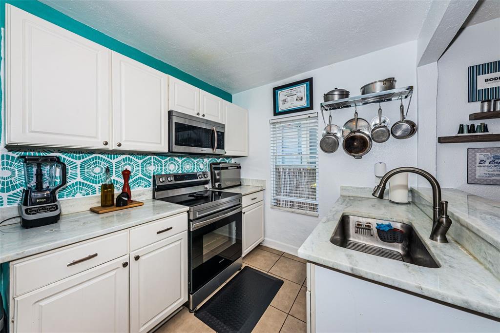 A kitchen features white cabinets, stainless steel appliances, a patterned backsplash, and a sink area — 547 15TH STREET N, ST PETERSBURG, FL