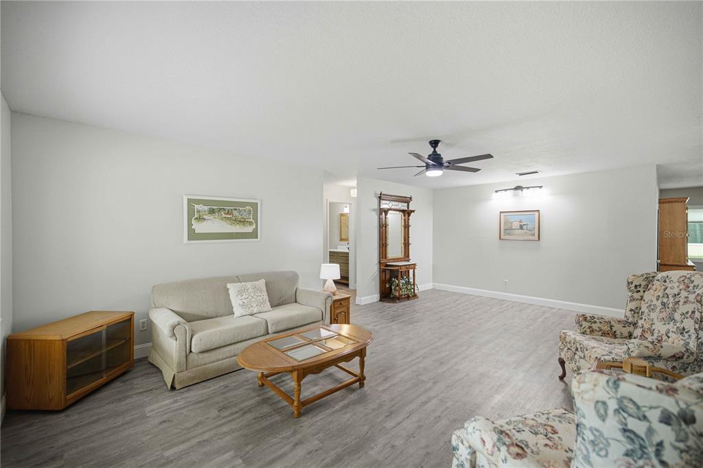 A living room features light gray walls, wood-look flooring, a sofa, and two floral armchairs — 8891 SW 96TH LANE UNIT B, OCALA, FL