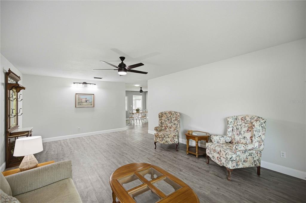 A living room features gray wood-look flooring, two floral armchairs, and a wooden coffee table — 8891 SW 96TH LANE UNIT B, OCALA, FL