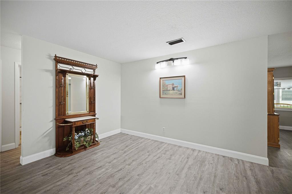 A dining room with light gray walls, wood-look flooring, a wall-mounted mirror, and a light fixture — 8891 SW 96TH LANE UNIT B, OCALA, FL