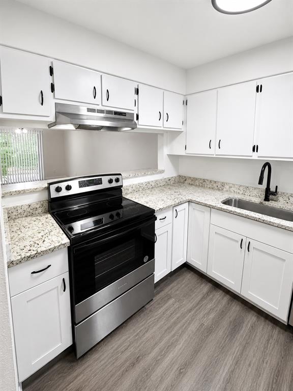 A kitchen features white cabinets, granite countertops, stainless steel appliances, and wood-look flooring — 1717-1717 NE 2ND STREET, OCALA, FL