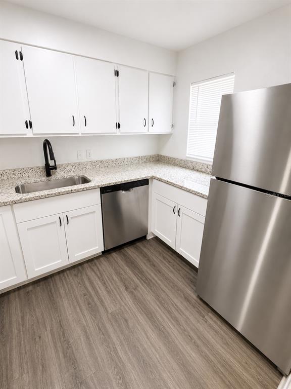 A kitchen features white cabinets, granite countertops, stainless steel appliances, and wood-look flooring — 1717-1717 NE 2ND STREET, OCALA, FL
