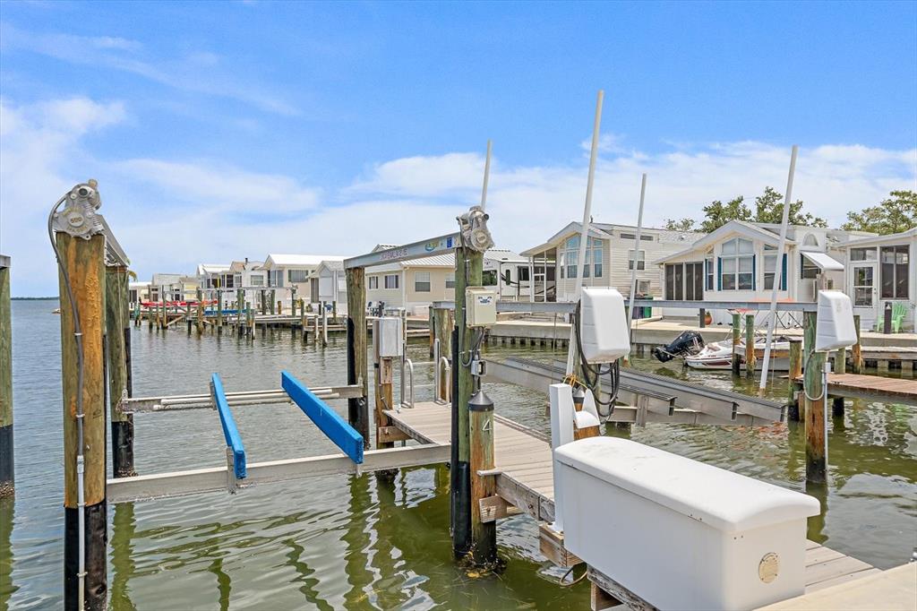A boat lift sits at the end of a wooden dock in front of mobile homes — 4 BASIN STREET, PALMETTO, FL