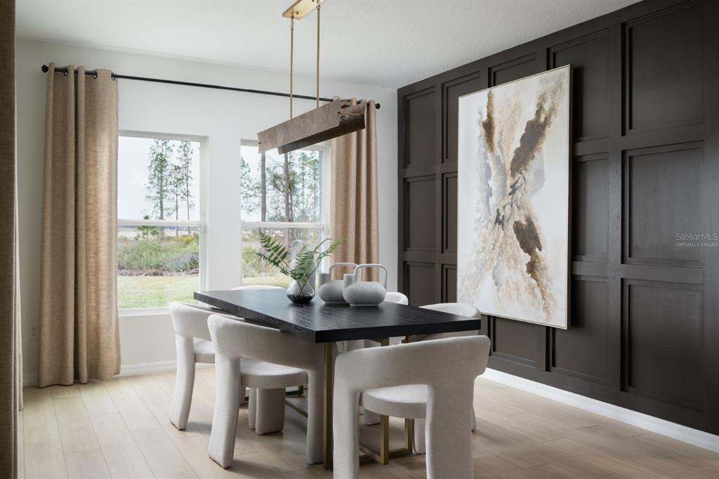 A dining room features a dark paneled accent wall, a rectangular table, and modern chairs — 2338 STILLVIEW PASS, ZEPHYRHILLS, FL