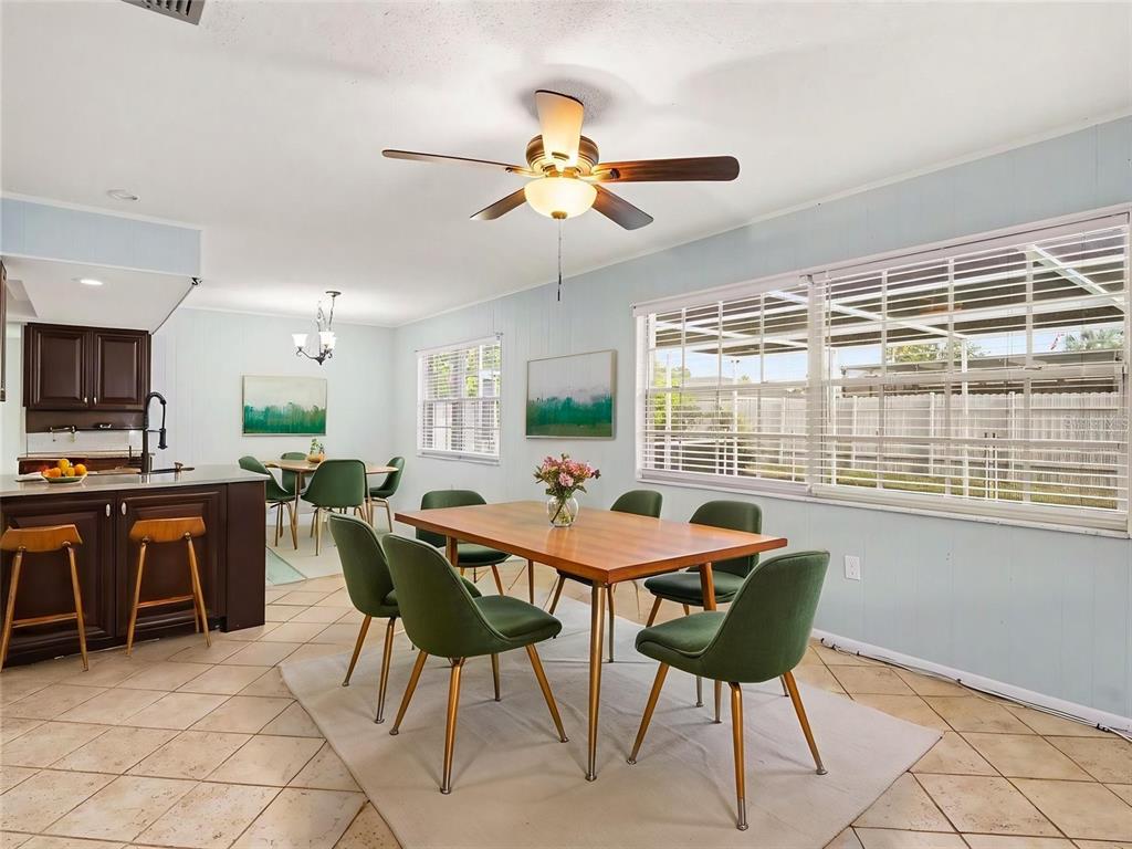 A dining area with a wooden table, green chairs, and a kitchen island with stools — 3907 23RD AVENUE W, BRADENTON, FL