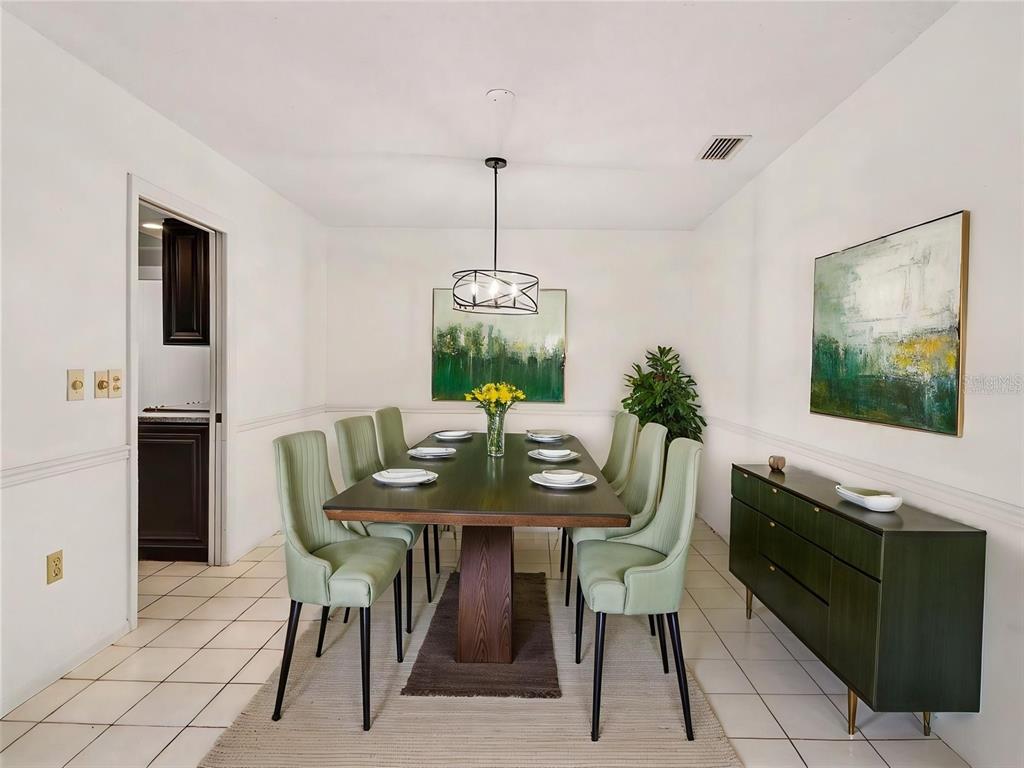 A dining room features a dark wood table, light green chairs, and a green sideboard — 3907 23RD AVENUE W, BRADENTON, FL